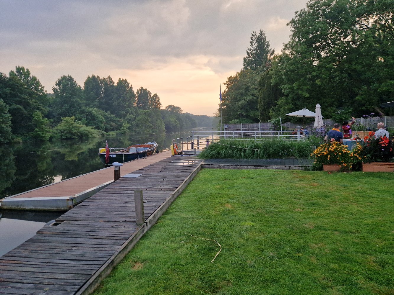 Wooden pontoon at dusk with boats moored along the Yare